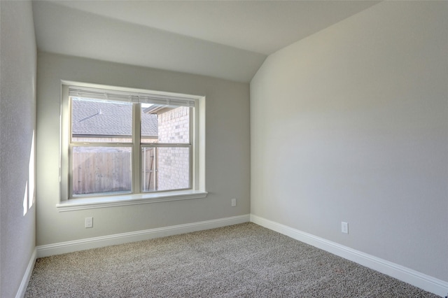 empty room featuring carpet floors, baseboards, and vaulted ceiling