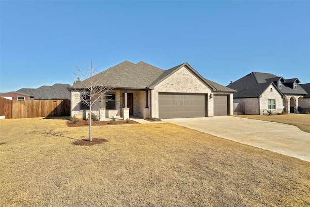 view of front facade featuring brick siding, roof with shingles, concrete driveway, an attached garage, and fence