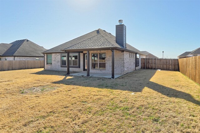 back of property featuring a yard, brick siding, a patio area, and a fenced backyard