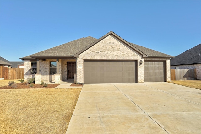 view of front of property with a garage, brick siding, and fence