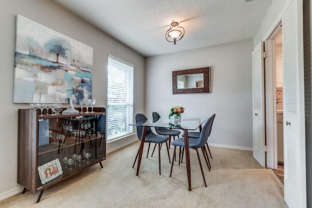 dining room featuring light carpet and a textured ceiling