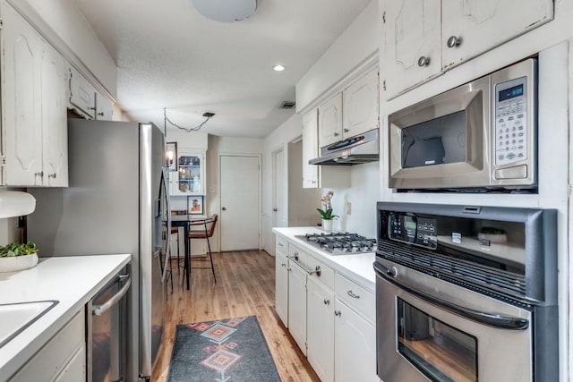 kitchen featuring stainless steel appliances, white cabinets, and light wood-type flooring