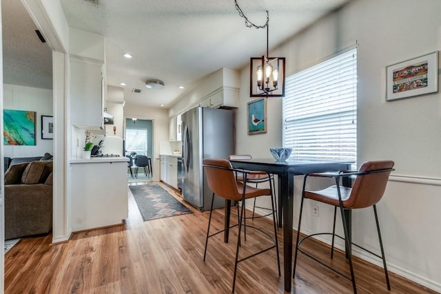 dining room featuring a notable chandelier, a textured ceiling, and light wood-type flooring