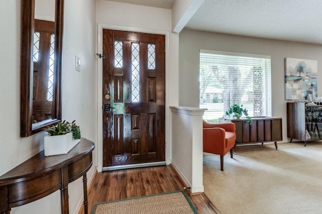 entryway with a textured ceiling and dark colored carpet