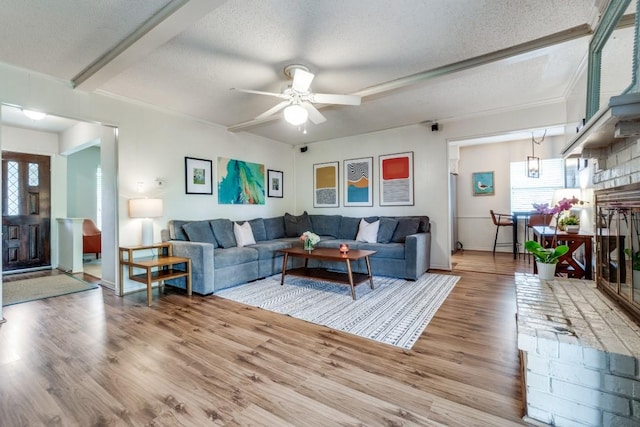 living room featuring ceiling fan, wood-type flooring, and a textured ceiling