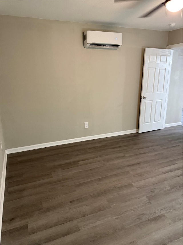 empty room featuring hardwood / wood-style flooring, an AC wall unit, and ceiling fan