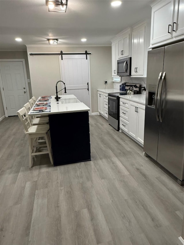 kitchen featuring sink, a barn door, white cabinets, and appliances with stainless steel finishes