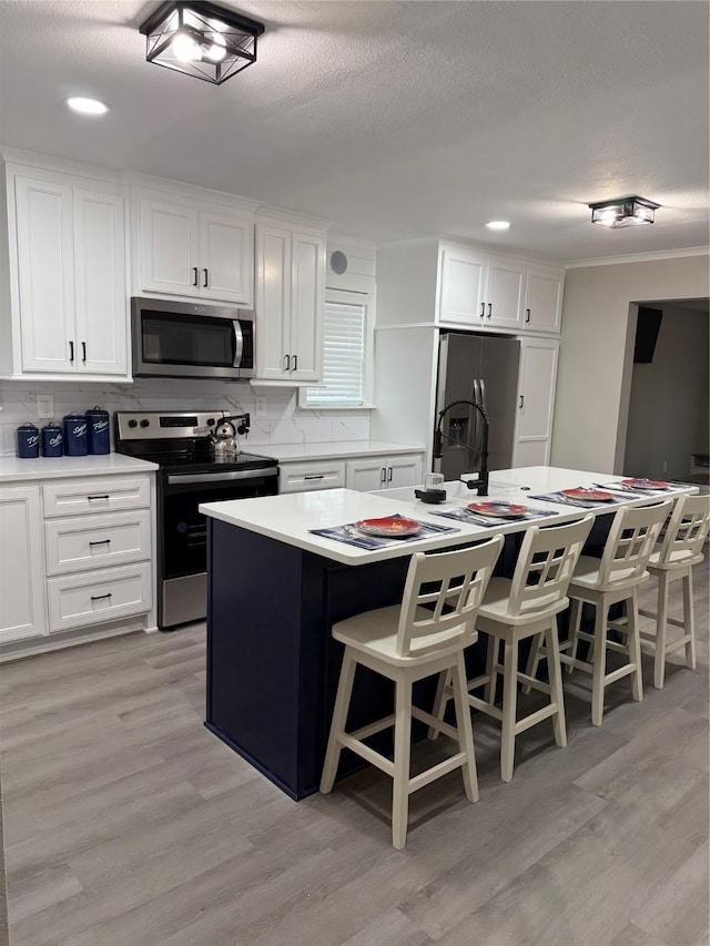 kitchen with white cabinetry, stainless steel appliances, a kitchen breakfast bar, and a center island