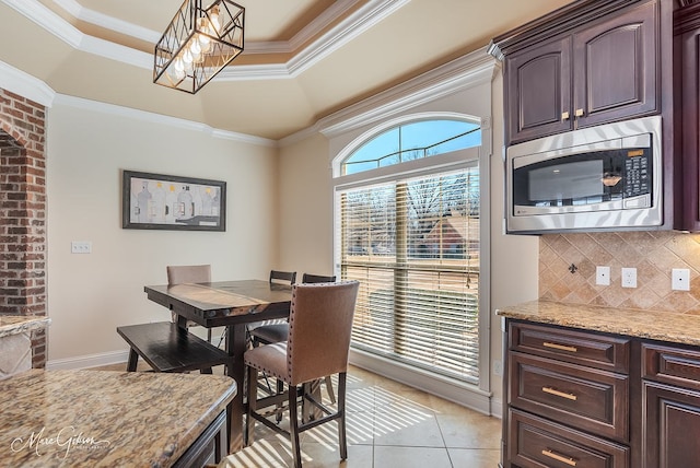 tiled dining area with an inviting chandelier, a tray ceiling, and ornamental molding