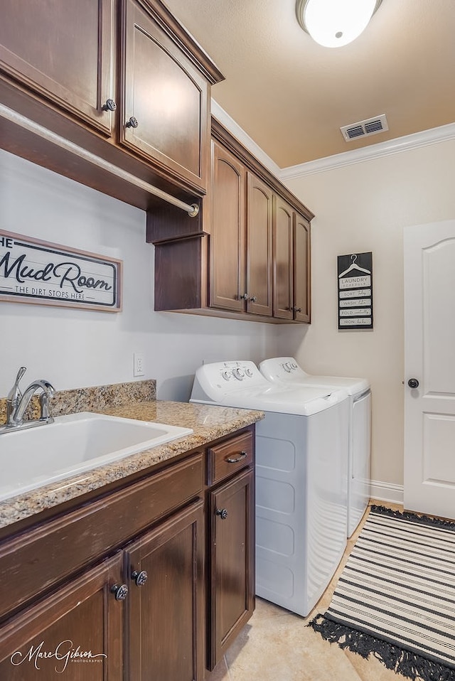 washroom featuring cabinets, ornamental molding, sink, and washing machine and clothes dryer