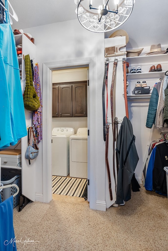 clothes washing area featuring cabinets, a chandelier, and washer and clothes dryer