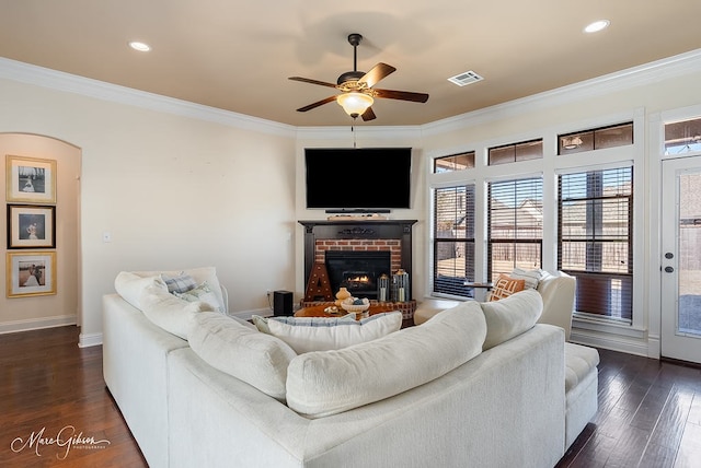 living room featuring crown molding, a fireplace, dark hardwood / wood-style flooring, and ceiling fan