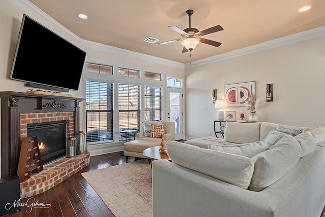 living room featuring a fireplace, crown molding, dark wood-type flooring, and ceiling fan