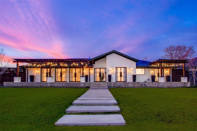 back house at dusk with a yard and a pergola