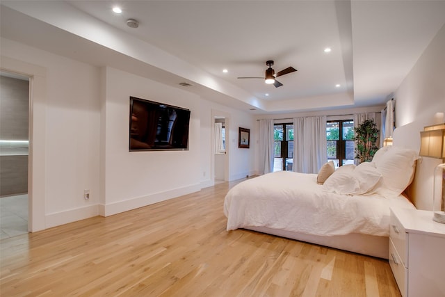 bedroom with ceiling fan, a tray ceiling, access to outside, and light wood-type flooring