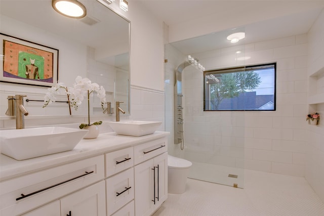 bathroom featuring tile walls, vanity, a tile shower, tile patterned floors, and toilet