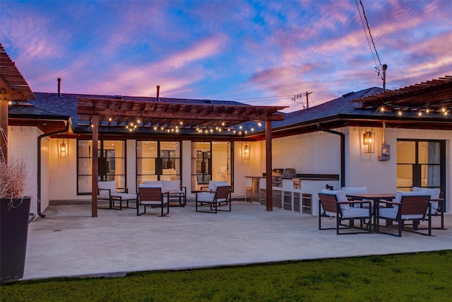 back house at dusk with area for grilling, a pergola, and a patio area