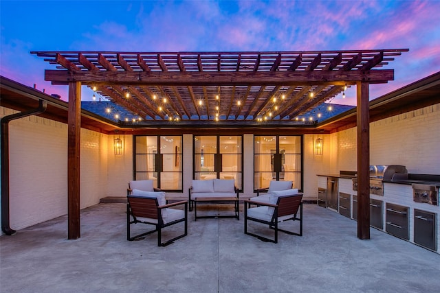 patio terrace at dusk with area for grilling, a pergola, outdoor lounge area, and an outdoor kitchen