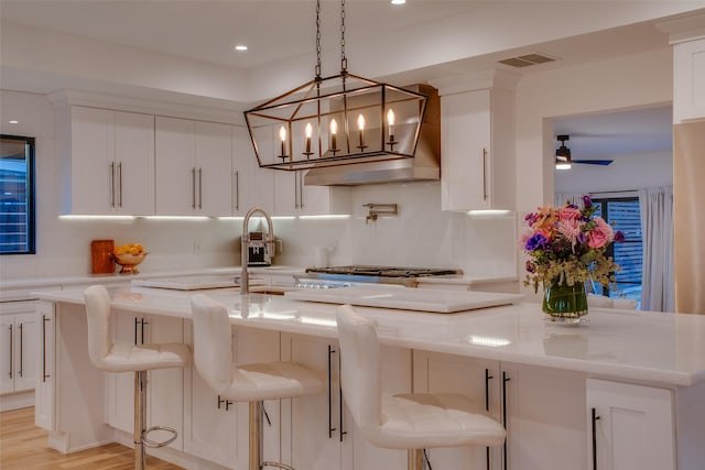 kitchen featuring white cabinetry, light stone countertops, a breakfast bar area, and backsplash