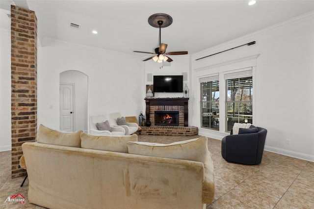 living room featuring tile patterned flooring, crown molding, a fireplace, and ceiling fan