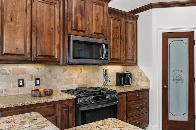 kitchen featuring stainless steel appliances, light stone countertops, and decorative backsplash