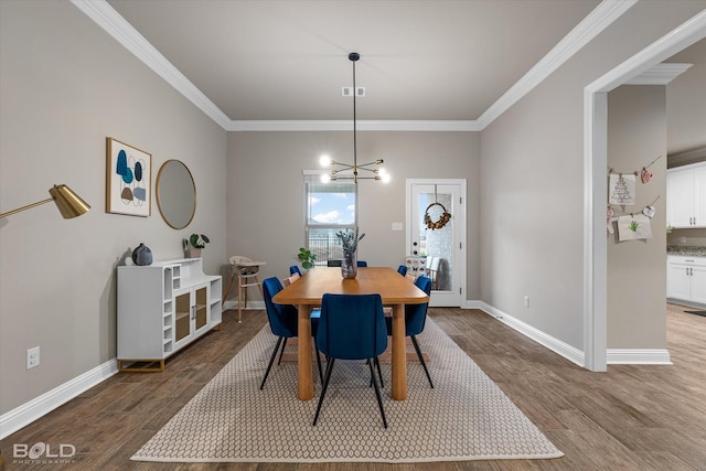 dining area featuring wood-type flooring, ornamental molding, and a notable chandelier