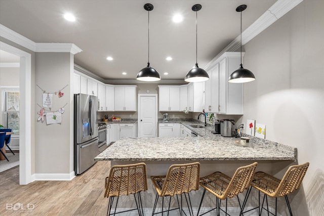 kitchen featuring appliances with stainless steel finishes, sink, white cabinets, ornamental molding, and kitchen peninsula