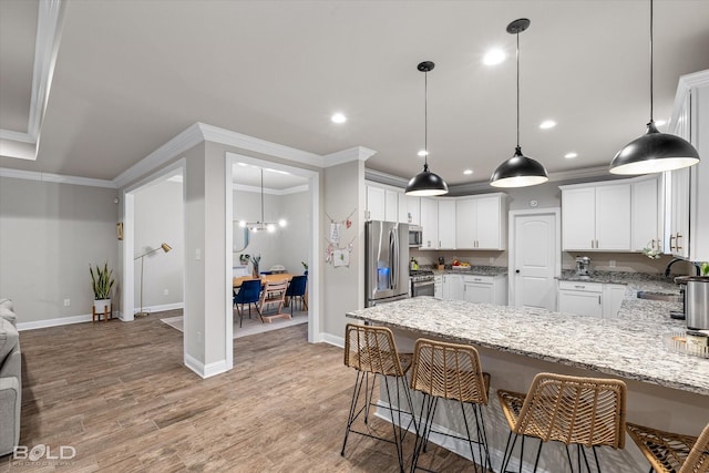 kitchen featuring appliances with stainless steel finishes, white cabinetry, sink, ornamental molding, and light hardwood / wood-style flooring