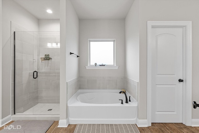 bathroom with hardwood / wood-style flooring and shower with separate bathtub