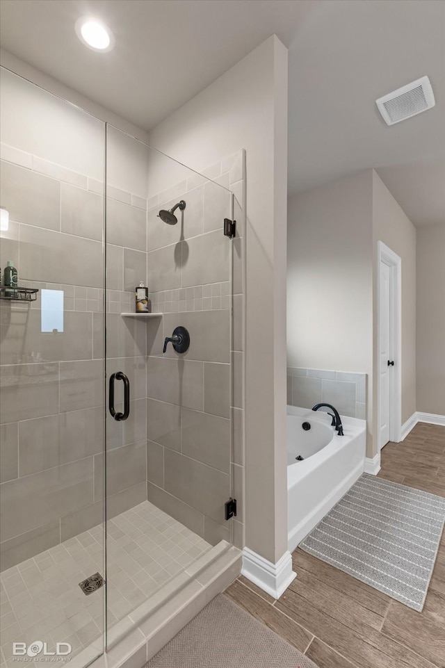 bathroom with hardwood / wood-style flooring and independent shower and bath