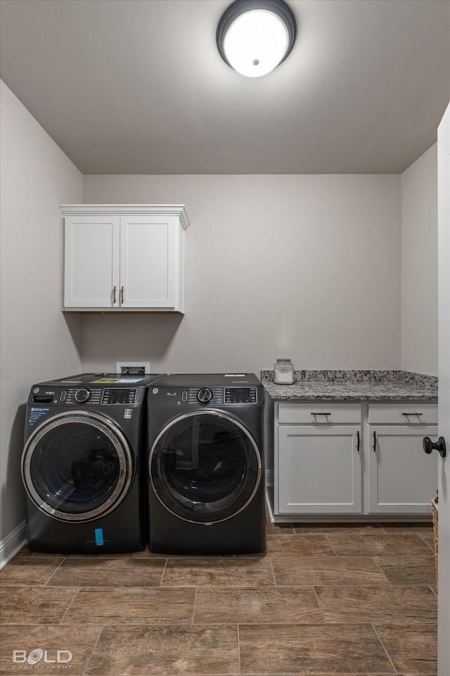 clothes washing area with cabinets and separate washer and dryer