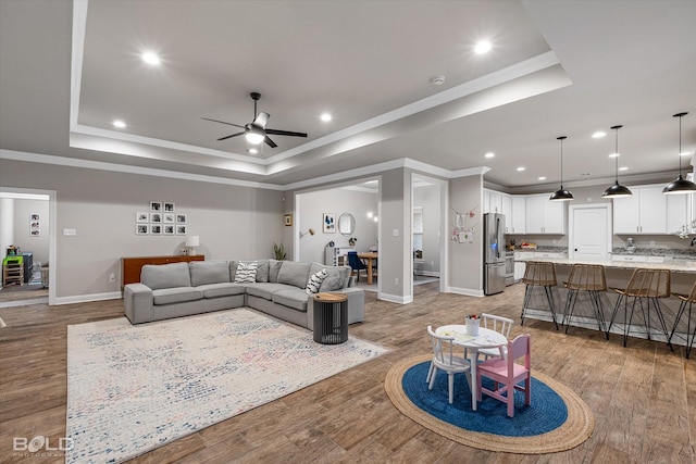 living room with hardwood / wood-style flooring, ornamental molding, and a tray ceiling