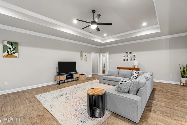 living room with a raised ceiling, crown molding, and hardwood / wood-style flooring