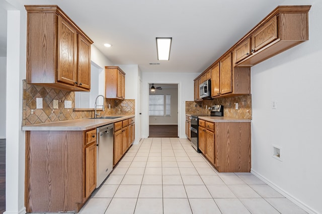 kitchen featuring sink, backsplash, light tile patterned floors, ceiling fan, and stainless steel appliances