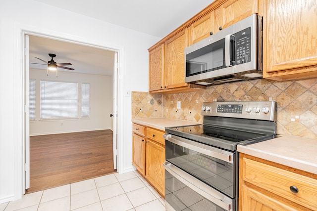 kitchen featuring light tile patterned flooring, ceiling fan, appliances with stainless steel finishes, and backsplash