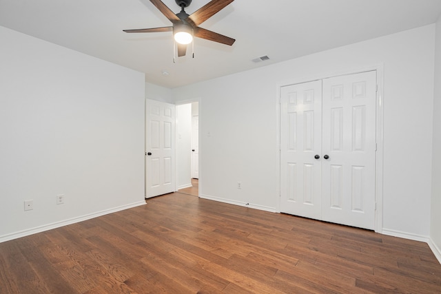 unfurnished bedroom with ceiling fan, dark hardwood / wood-style flooring, and a closet