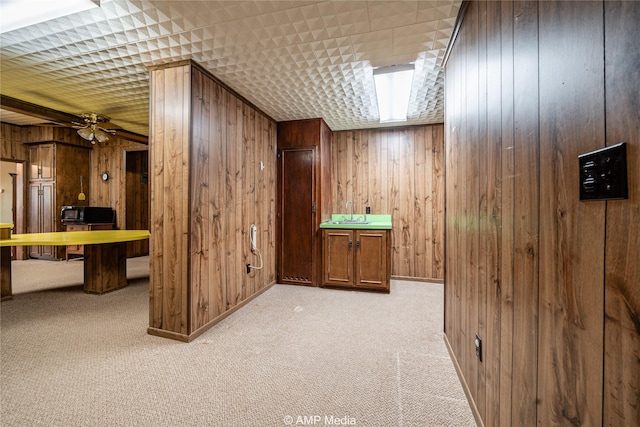 additional living space with ceiling fan, light colored carpet, and wooden walls