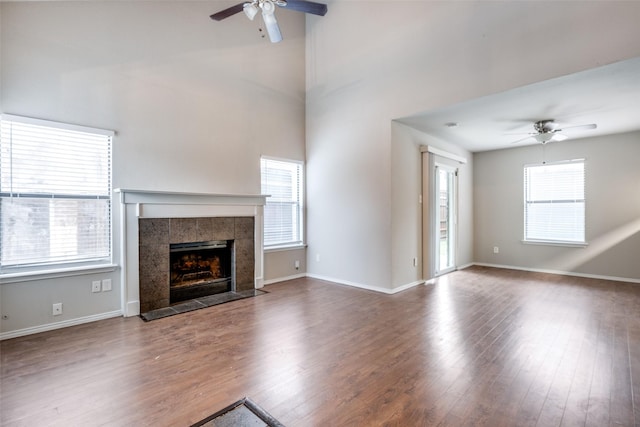 unfurnished living room featuring a tile fireplace, hardwood / wood-style floors, and ceiling fan