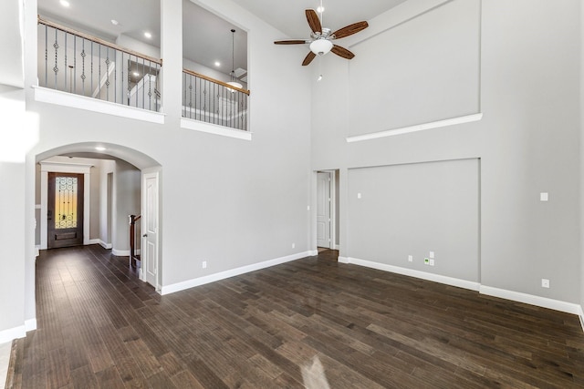 unfurnished living room featuring dark wood-type flooring and ceiling fan