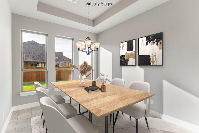 dining space featuring light tile patterned flooring, a notable chandelier, and a tray ceiling