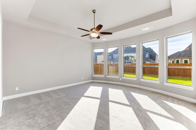 carpeted empty room featuring a mountain view, a tray ceiling, and ceiling fan