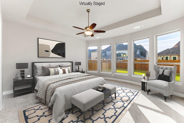 bedroom featuring a mountain view, a tray ceiling, and light colored carpet