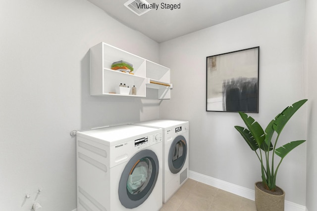 laundry area featuring washing machine and dryer and light tile patterned floors