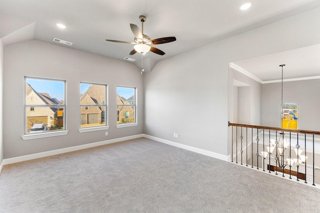 carpeted spare room featuring vaulted ceiling, ornamental molding, and ceiling fan