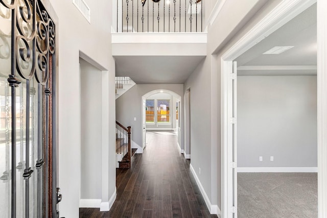 foyer entrance with dark wood-type flooring and a towering ceiling