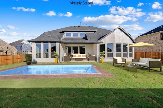 back of property with outdoor lounge area, a fenced in pool, and a lawn