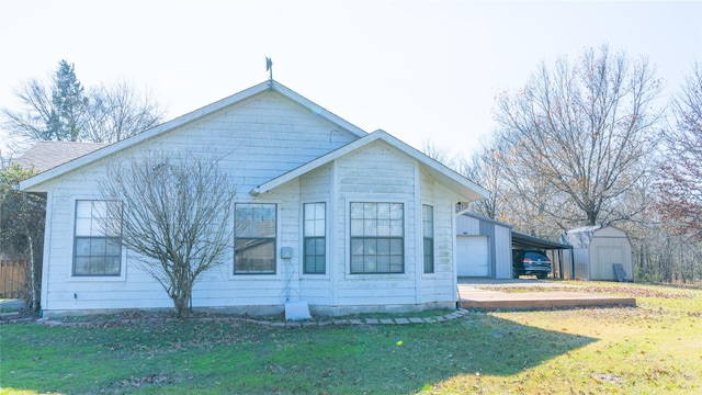 view of side of home with a carport, a garage, a yard, and a shed