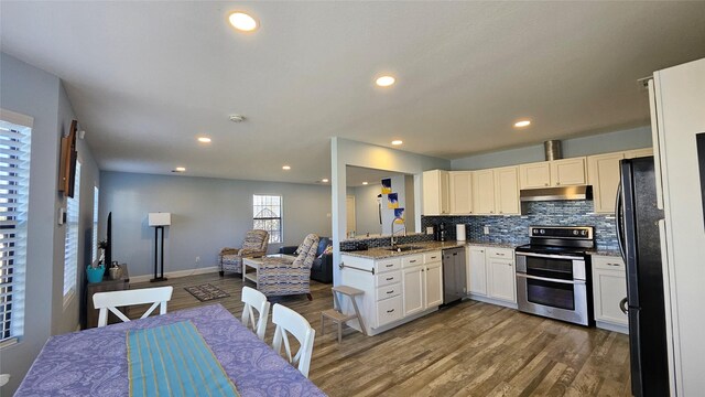 kitchen with sink, white cabinets, stainless steel appliances, hardwood / wood-style floors, and backsplash