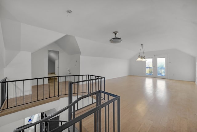 bonus room featuring vaulted ceiling, light wood-type flooring, and french doors