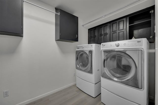 laundry area with cabinets, washing machine and dryer, and light wood-type flooring